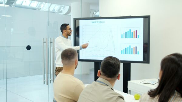 Group of professionals analyzing a digital dashboard on a screen.